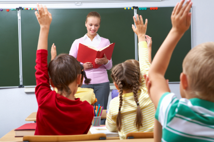 Rear view of pupils raising arms during the lesson with teacher looking at them