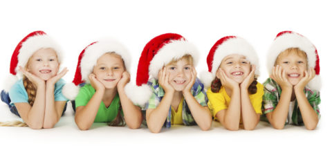 Group of happy Christmas kids in Santa hat lying down. White background.