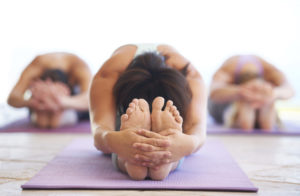 Young yoga instructor leading a class in stretching