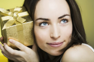 curious smiling young woman with a gift box in her hands
