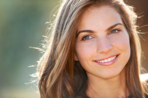 Portrait of a young woman smiling while outdoor in the sun.