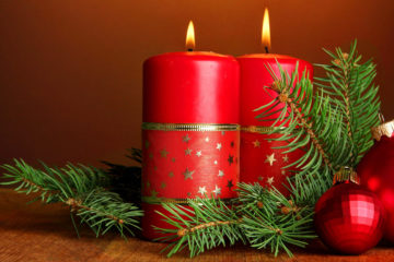 Two candles and christmas decorations, on brown background