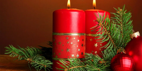 Two candles and christmas decorations, on brown background
