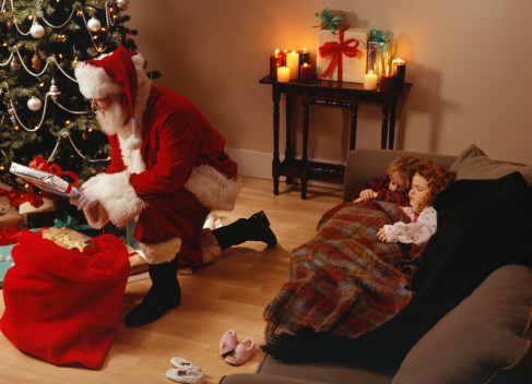 Santa Claus putting presents under Christmas tree